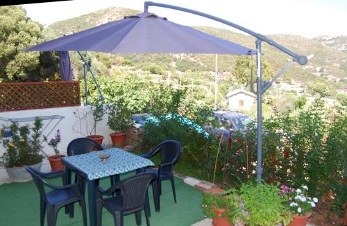 uma mesa e cadeiras sob um guarda-sol num jardim em Il Rifugio del vecchio Bandito em Iglesias