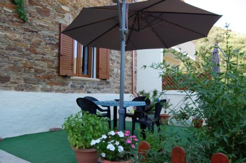 una mesa y sillas con una sombrilla en el jardín en Il Rifugio del vecchio Bandito, en Iglesias