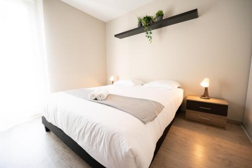 une chambre avec un grand lit avec des draps blancs dans l'établissement Chez Léon - Métro, Bus, Garage Double, 6 Personnes, à Villeurbanne