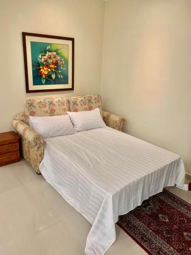 a bedroom with a bed and a couch with a white blanket at Puncak Villa 10-20pax in Kuala Kangsar