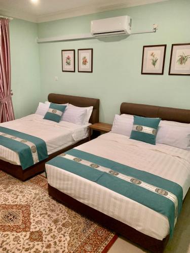 two beds sitting next to each other in a room at Puncak Villa 10-20pax in Kuala Kangsar