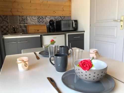 une table avec trois tasses et une rose dans une cuisine dans l'établissement Une Pause Douceur - Suite All in Wood, à Eyguières