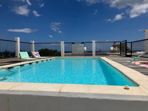 una piscina con acqua blu di fronte a una recinzione di Seaview Terrace Appartement a Flic-en-Flac