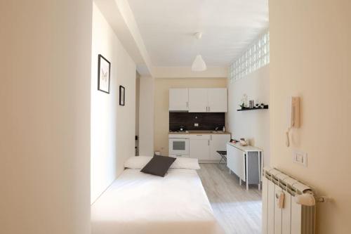 a white room with a bed and a kitchen at Grazioso Appartamento Trastevere in Rome