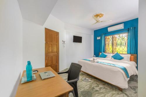 um quarto com uma cama, uma mesa e uma janela em The Sequeira Goa em Majorda