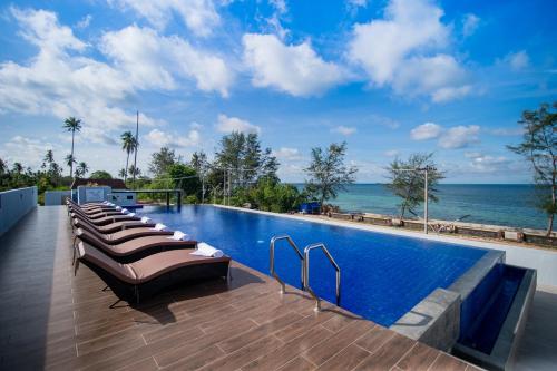 a swimming pool with lounge chairs next to the ocean at One of A Kind Resort @Trikora Beach - Bintan in Telukdalam