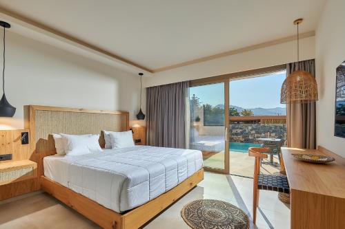 a bedroom with a bed and a desk and a balcony at Sentido Amounda Bay in Amoudara Herakliou
