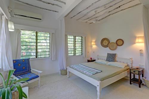 a bedroom with a bed and a chair and windows at Salama House - your peaceful, poolside retreat in Watamu