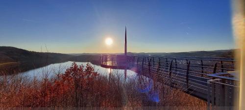 a bridge over a river with the sun in the background at Ferienwohnung Busch in Meinerzhagen