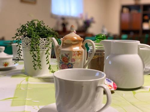 una mesa con tazas blancas y macetas. en Stabat Mater Casa di Preghiera en Valdragone