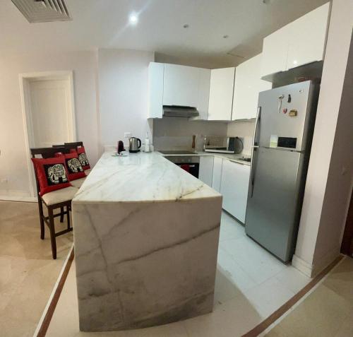 a kitchen with a stainless steel refrigerator and white cabinets at Luxury 2BD flat, steps from Sahl Hasheesh beach in Hurghada