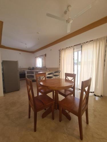 a dining room with a table and chairs and a kitchen at Linda's Little Lincoln in Watamu
