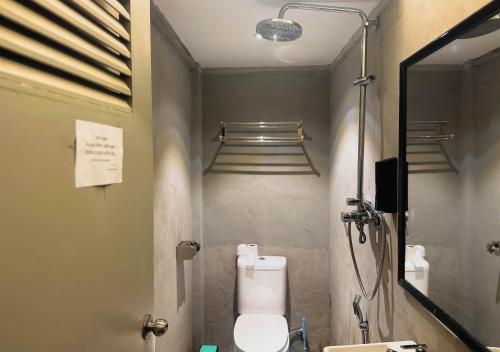 a bathroom with a toilet and a shower with a mirror at Arch Dormitorio Cenang in Pantai Cenang