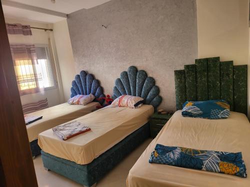 - une chambre avec 2 lits avec des coussins bleus dans l'établissement Appartement near airport ouled tayeb, à Al Hachlaf