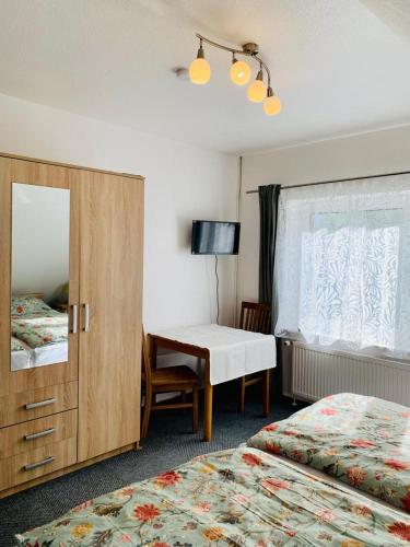 a hotel room with two beds and a desk and a mirror at Hotel Pension Schienfatt am Dornumersieler Tief in Dornum