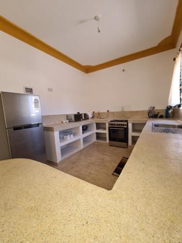 a kitchen with a refrigerator and a counter top at Linda's Little Lincoln in Watamu