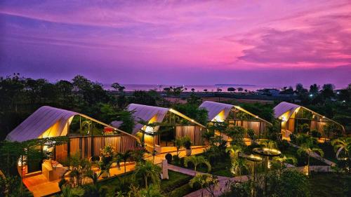 a row of domed buildings with a sunset in the background at Lucca Resort & Residence in Jepara