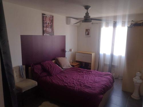 ein Schlafzimmer mit einem lila Bett und einem Fenster in der Unterkunft Jolie villa a 10 minutes de la mer pour vos vacances in Sauvian