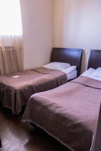 two beds in a hotel room with a window at Parvana Hotel in Gyumri