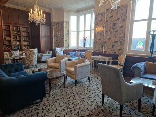 uma sala de estar com sofás e cadeiras e um lustre em The Orwell Hotel em Felixstowe
