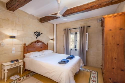 a bedroom with a large bed with a wooden headboard at Dar ta' Mansi Farmhouse with Private Pool in Għarb