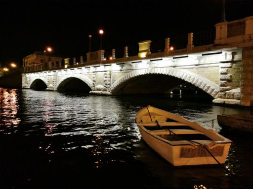 a boat in the water in front of a bridge at DIONISO Bed & Wellness in Taranto