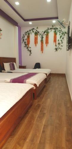 Zimmer mit 3 Betten mit Karotten an der Wand in der Unterkunft LẠI NGUYỄN BOUTIQUE HOTEL in Cần Thơ