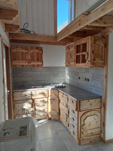 une cuisine avec des armoires en bois et un comptoir dans l'établissement Le petit grenier, à Saint-Bonnet-en-Champsaur
