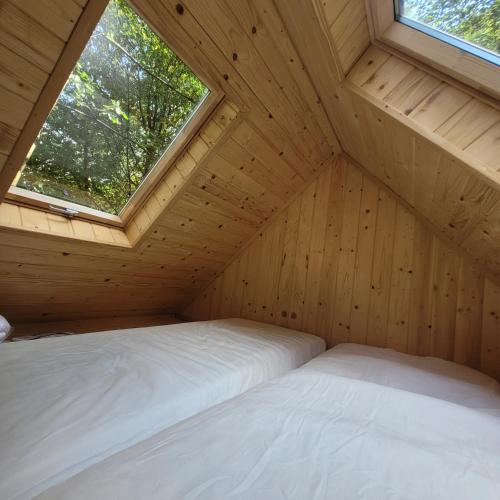 2 Betten in einem Holzzimmer mit Fenster in der Unterkunft Zagroda Zabłocie 