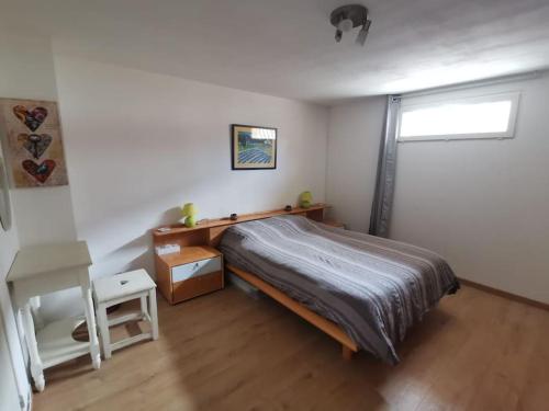 Un dormitorio con una cama y un escritorio y una ventana. en La Casetta T2 RDC avec jardin à Ruoms, en Ruoms