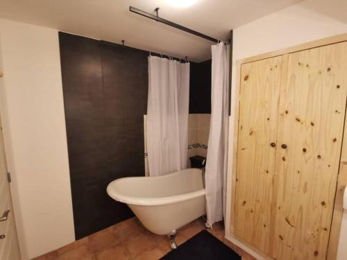 Un baño con bañera blanca y puerta de madera. en La Casetta T2 RDC avec jardin à Ruoms, en Ruoms