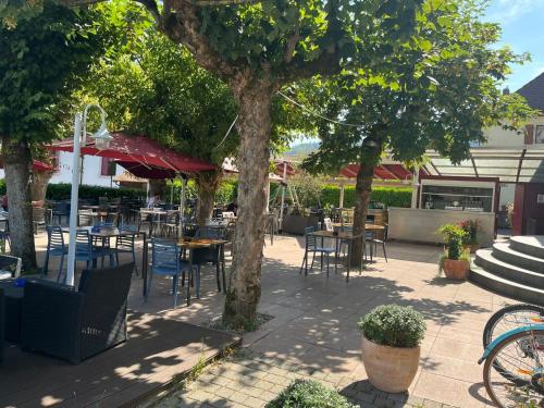 an outdoor patio with tables and chairs and trees at Hotel de ville d'Yvonand in Yvonand