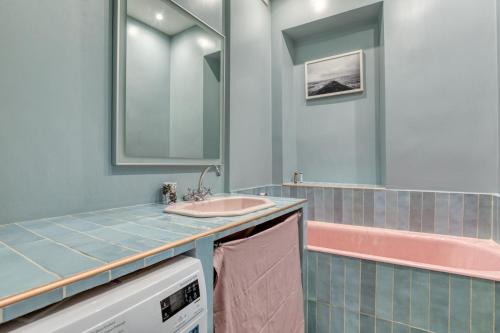La salle de bains est pourvue d'un lavabo et d'une baignoire rose. dans l'établissement Outstanding charming flat - Heart of Saint-Honoré, à Paris