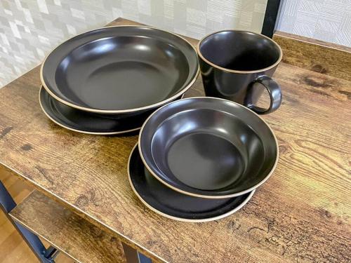 three black bowls and cups on a wooden counter at Villa Verde 那須 in Nasu