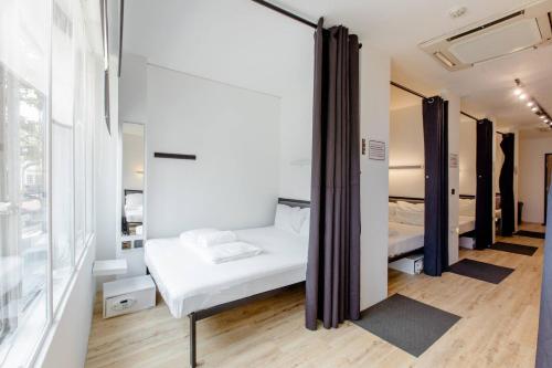 a room with a white bed and a mirror at RadZone Hostel in Singapore