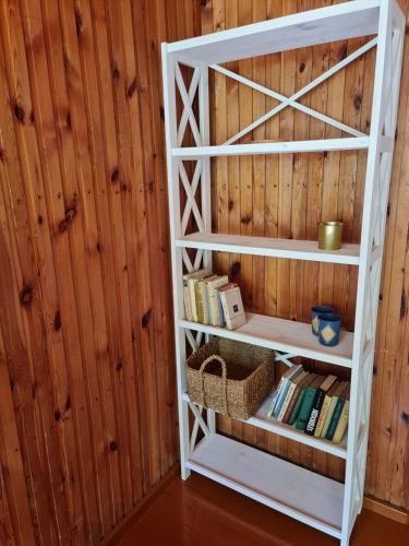 a white book shelf in a room with wooden walls at Viesuliškės Lakeside Glamping in Lakaja