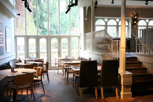 un restaurante con mesas, sillas y ventanas grandes en Milsoms en Dedham