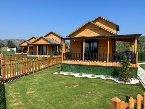 uma fila de chalés atrás de uma cerca de madeira em Lake house kayacık Resort em Dalaman