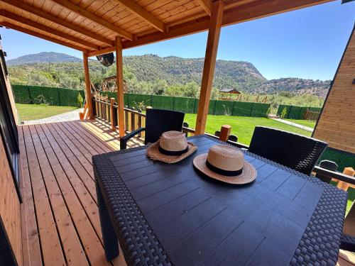 達拉曼的住宿－Lake house kayacık Resort，两顶帽子坐在甲板上的木桌旁