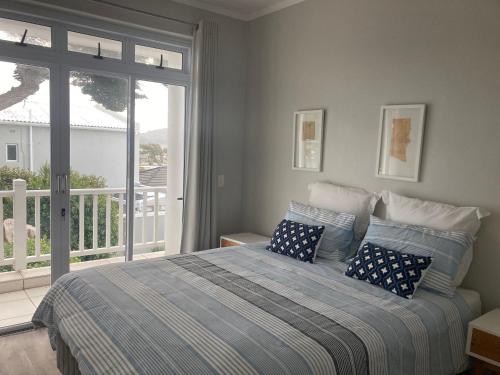 um quarto com uma cama com almofadas azuis e uma varanda em Restore your Soul, Boulders Beach, Simonstown em Simonʼs Town
