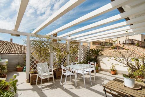 patio z białą pergolą, stołem i krzesłami w obiekcie Il Piccolo Attico w mieście Caltagirone