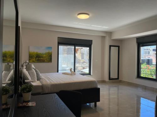 a bedroom with a bed and two windows at Mizirawi Historic Hotel in Ramallah