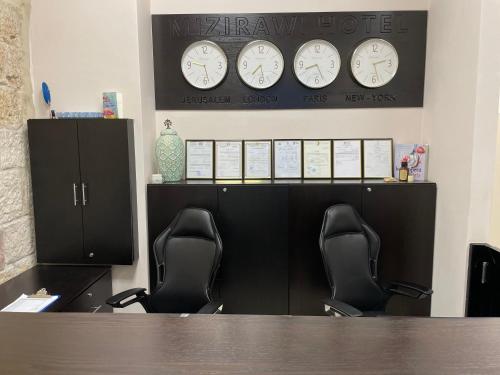 two chairs in an office with clocks on the wall at Mizirawi Historic Hotel in Ramallah