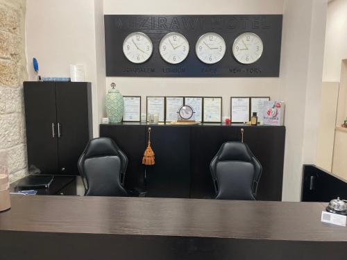 two chairs sitting at a counter with clocks on the wall at Mizirawi Historic Hotel in Ramallah