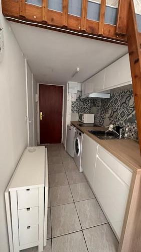 une petite cuisine avec des armoires blanches et un évier dans l'établissement Charmant studio Jean Médecin, à Nice