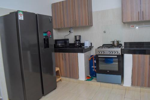 姆瓦帕的住宿－Happy Trails Home- Green Wood Estate Mtwapa，厨房配有不锈钢冰箱和炉灶。