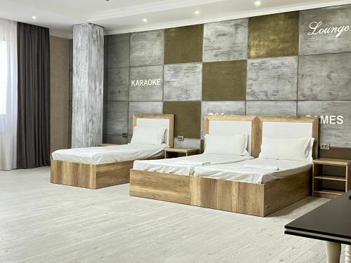 a bedroom with two beds and a wall at Dostar Inn in Shymkent