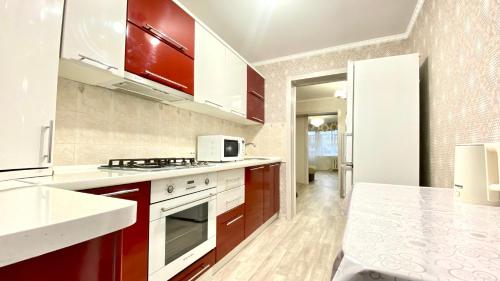 a kitchen with white counters and red cabinets at ГК ДОМ ДОСТЫК 3-комнатная в центре in Petropavlovsk