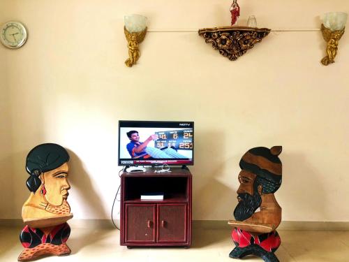 Dos estatuas de personas sentadas frente a un televisor. en Tranquil home near vagator beach, en Anjuna