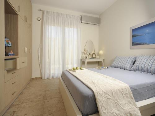 a white bedroom with a large bed and a window at Villa Avra in Panormos Rethymno